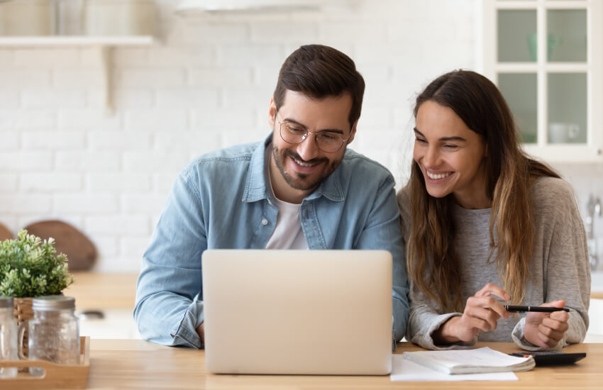 A couple smiling by watching at their laptop