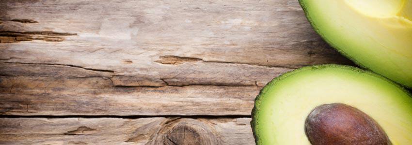 An avocado split in two resting on a wooden table