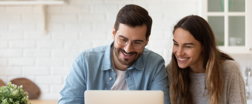 A couple smiling by watching at their laptop