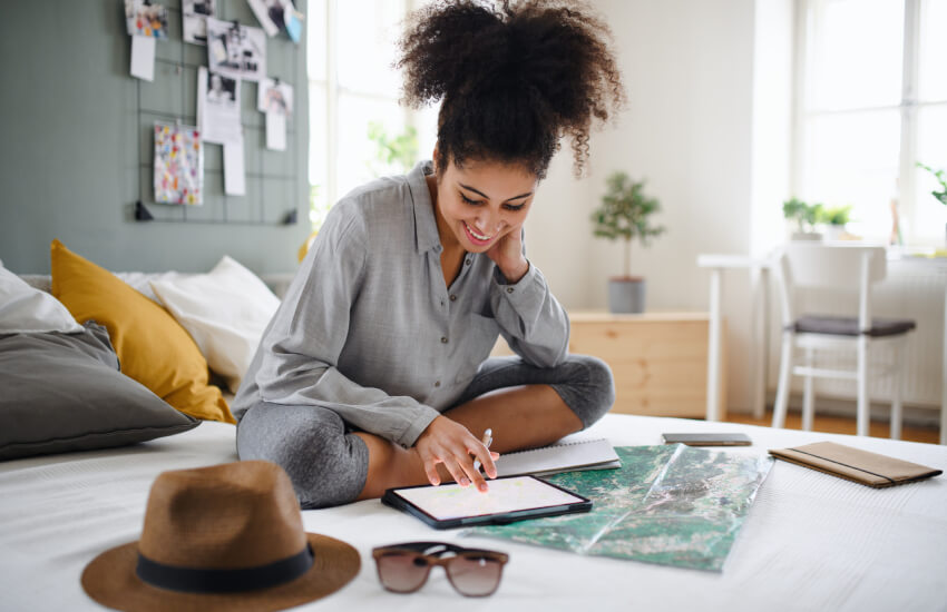 smiling woman sitting on her bed looking at her notebooks